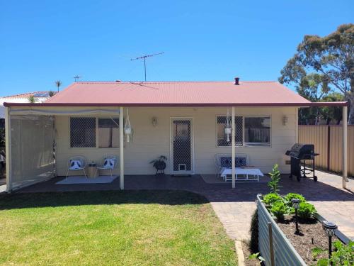 a small white house with a pink roof at G&R Beach Cottage in Warnbro
