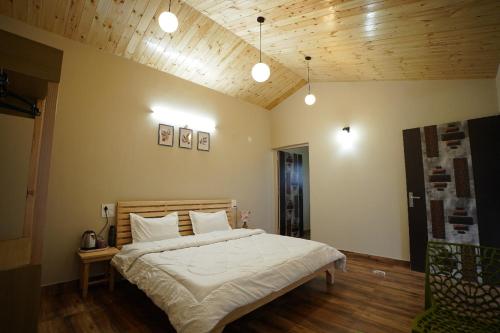 a bedroom with a bed with white sheets and wooden ceilings at The Northern Nook in Mukteshwar