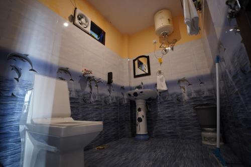 a bathroom with a toilet and a wall with penguins on it at The Northern Nook in Mukteshwar