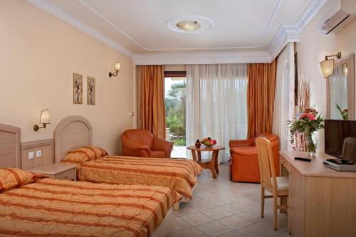 a hotel room with two beds and a television at Seydnaya Apartments & Studios in Neos Marmaras