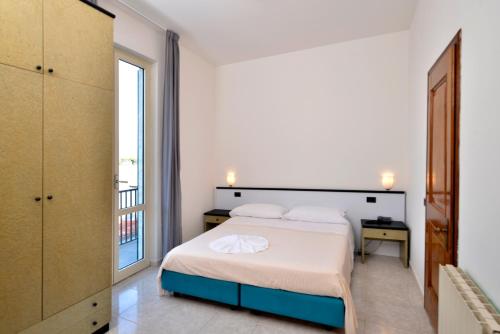 a white bedroom with a bed and a window at Hotel Garden Bocca di Magra in Bocca di Magra