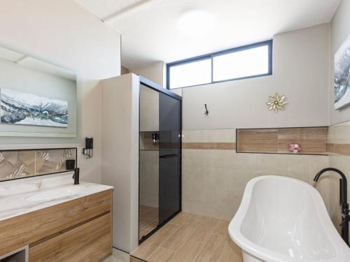 a bathroom with a tub shower and a toilet at Calypso Sunset Accommodation in Langebaan