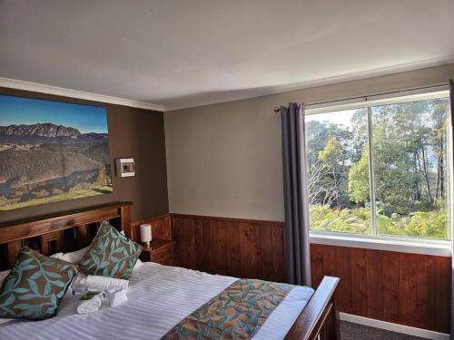 a bedroom with a bed and a large window at Cradle Alpine Retreat in Moina