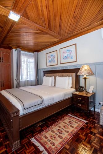 a bedroom with a large bed with a wooden ceiling at Cozy Stead Hotel - Garden House, Gigiri in Nairobi