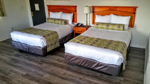 two beds in a hotel room with wooden floors at Jewel City Inn in Glendale