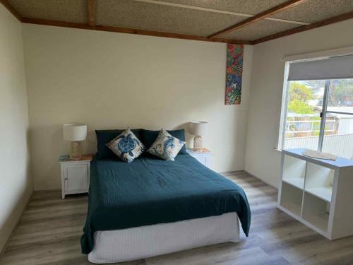 a bedroom with a bed with blue sheets and a window at Cervantes Beach Shack in Cervantes