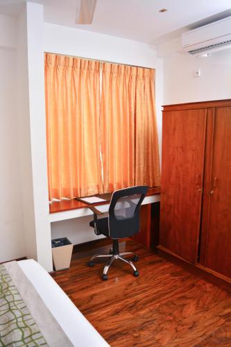 a bedroom with a desk and a chair in front of a window at Unique Towers Luxury Boutique Suites in Colombo