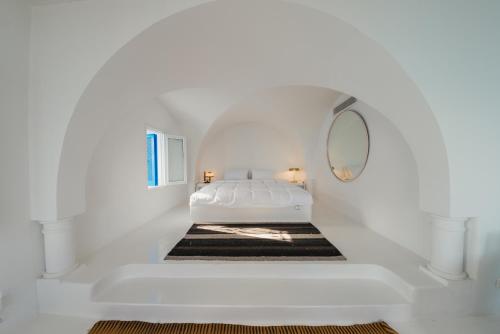 a white bedroom with a bed and a mirror at Villa Kahina in Carthage