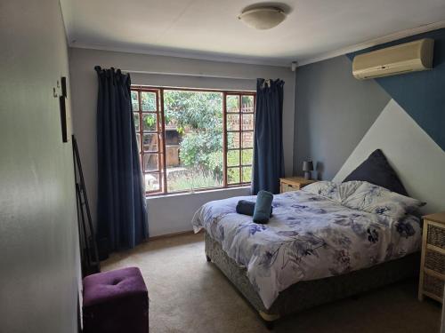 a bedroom with a bed and a window at Spacious & serene townhouse getaway in Bloemfontein