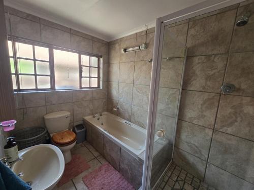 a bathroom with a shower and a tub and a sink at Spacious & serene townhouse getaway in Bloemfontein