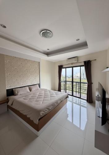 a bedroom with a large bed and a balcony at Phratamnak Grand Apartments - Cozy Beach in Pattaya South