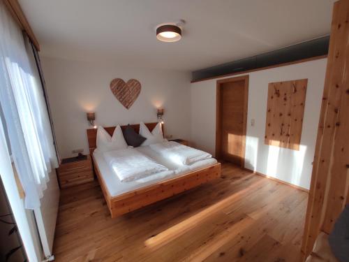 a bedroom with a bed with white sheets and a wooden floor at Jagerhof in Walchsee