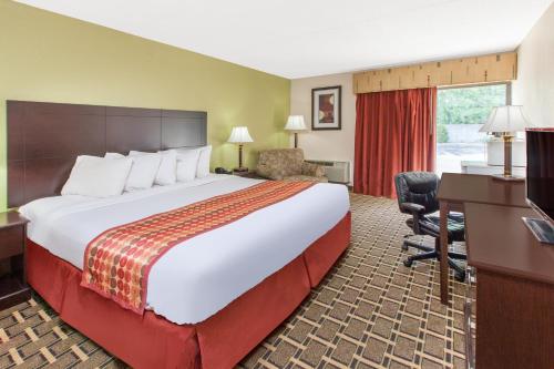 A bed or beds in a room at Days Inn & Suites by Wyndham Madison Heights MI