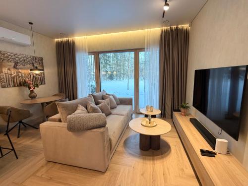 ein Wohnzimmer mit Sofa und Flachbildfernseher in der Unterkunft Pine Forest Residence in Melnragė
