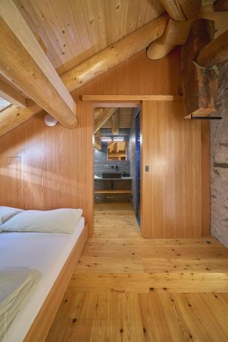 a bedroom with a bed and wooden walls and wooden floors at BnB Ai Cav Calanca in Arvigo