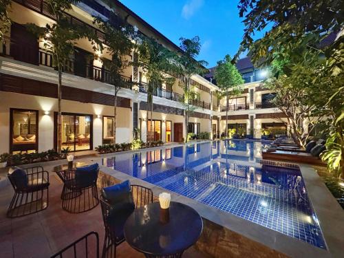 a swimming pool with tables and chairs next to a building at Emerald Angkor Siem Reap in Siem Reap