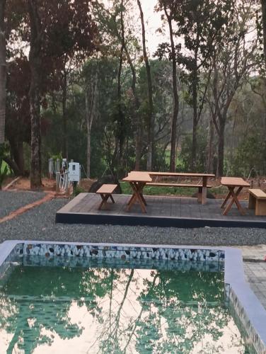 a picnic table and bench next to a pond at The Cool Cottage, Pool Extra, at gaya3farms in Palakkad