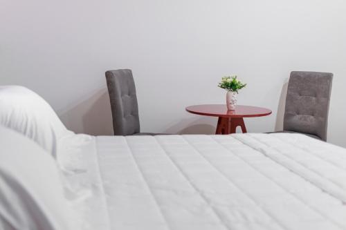 a white bed with two chairs and a table at Hotel Terceiro Milênio II in Brumado