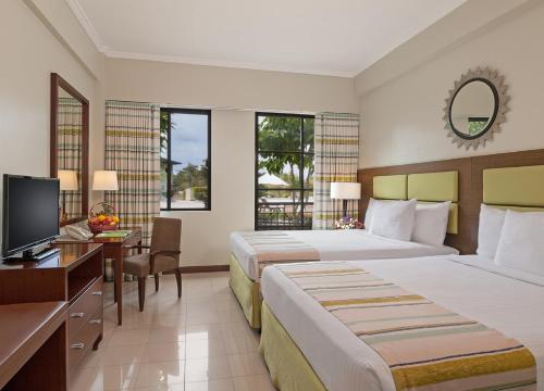 a hotel room with two beds and a desk and a television at Holiday Inn & Suites Batangas LimaPark by IHG in Batangas City