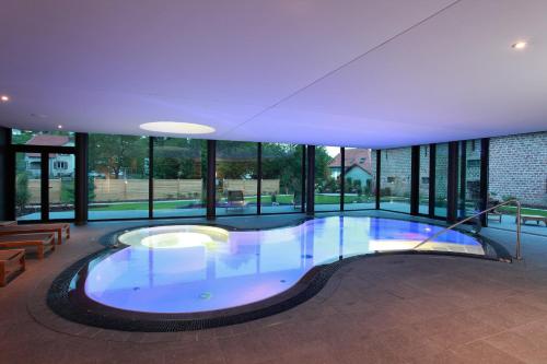 a large swimming pool in a building with windows at L'auberge Du Cheval Blanc et Spa in Lembach