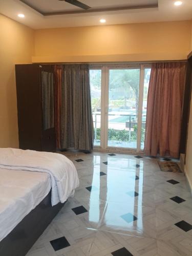 a bedroom with a bed and a large window at Riyank Farms in Patna