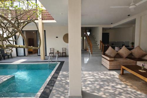 a villa with a swimming pool and a living room at Gatch Villa in Unawatuna