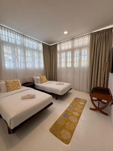 a bedroom with two beds and a table and windows at Sunset Beach Retreat & Beach Bistro in Batu Ferringhi