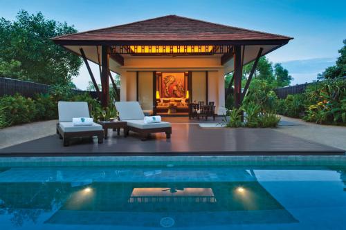 a gazebo with two chairs and a pool at Banyan Tree Lang Co in Hue