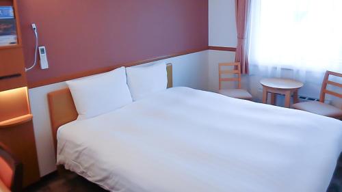 a bedroom with a white bed and a table and a window at Toyoko Inn Fujisan Numazu eki Kita guchi No 2 in Numazu