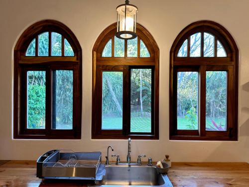 a kitchen with a sink and four windows at Van Kouwenhoven Hostel in Diriamba