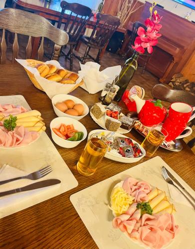 a wooden table topped with plates of food and drinks at Hotel & Restaurant Adolfovský Dvůr in Adolfov