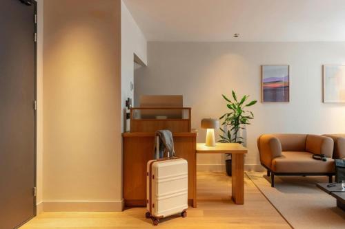a living room with a suitcase and a chair at Hotel Middelland Rotterdam in Rotterdam