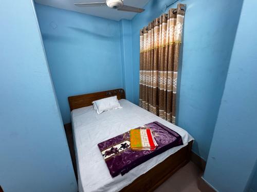 a small bedroom with a bed in a blue room at Hotel Shopno Abasik in Dhaka