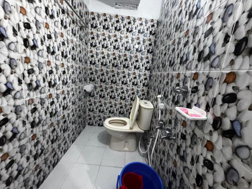 a bathroom with a toilet and a tiled wall at Hotel Shopno Abasik in Dhaka