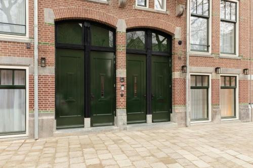 two green doors on the side of a brick building at Hotel Middelland Rotterdam in Rotterdam