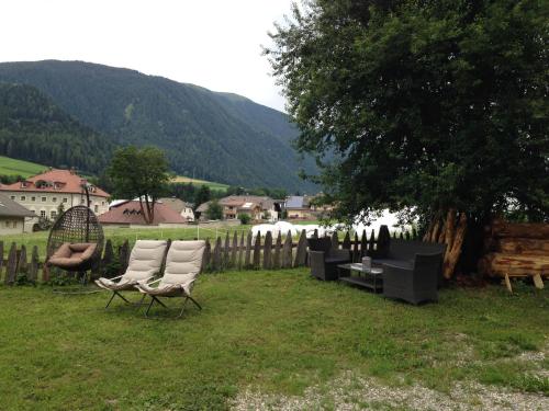 two chairs and a table in a yard next to a fence at Apartments Resi in Rasùn di Sotto