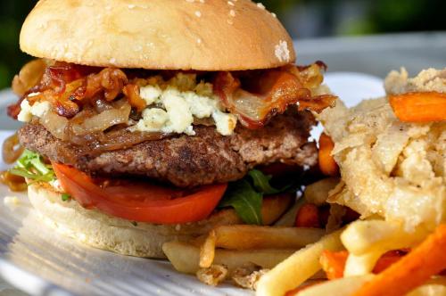 a hamburger with bacon and tomatoes and french fries at Sunshine Suites Resort in George Town