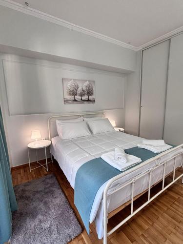 a bedroom with a white bed with a blue blanket at Relax - Patras Apartment in Patra