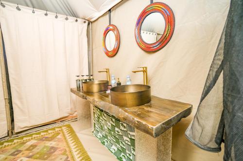 a bathroom with a sink and a mirror at Malaika Ndutu Luxury Camp in Sinoni
