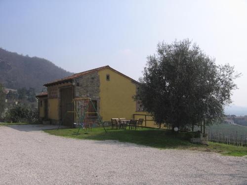 una casa amarilla con un parque infantil junto a un árbol en Il Castagneto, en Teolo