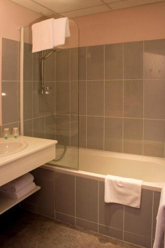 a bathroom with a shower and a tub and a sink at Hôtel Majestic in Lourdes
