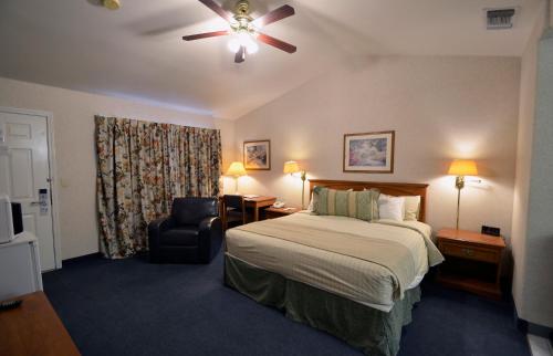 a hotel room with a bed and a chair at Garden Inn and Suites Fresno in Fresno