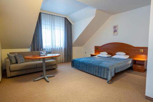 a bedroom with a bed and a table and a couch at Hotel Szelców in Lesko