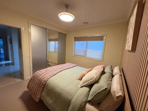 a bedroom with a bed with pillows and a window at The Nest at Forest Lake - Stylish Guest Suite in Kangaroo Flat