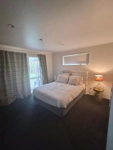 a bedroom with a large white bed and a window at Private Ensuite Room in Rolleston