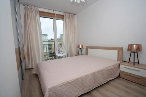 a bedroom with a bed and a large window at 100-SIO Apartamenty in Koszalin
