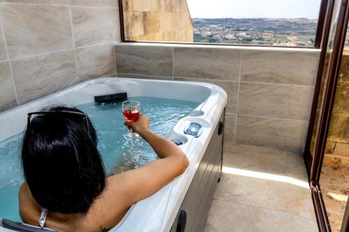 a woman holding a glass of wine in a bath tub at Ta Marija in Żebbuġ