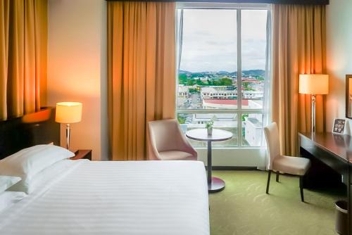 a hotel room with a bed and a large window at Pan Borneo Hotel Kota Kinabalu in Kota Kinabalu