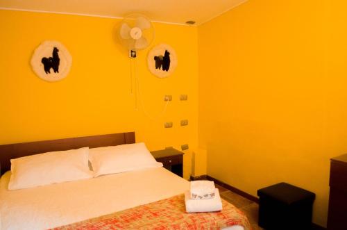 a yellow bedroom with a bed and a fan at Hostal Alabalti in San Pedro de Atacama
