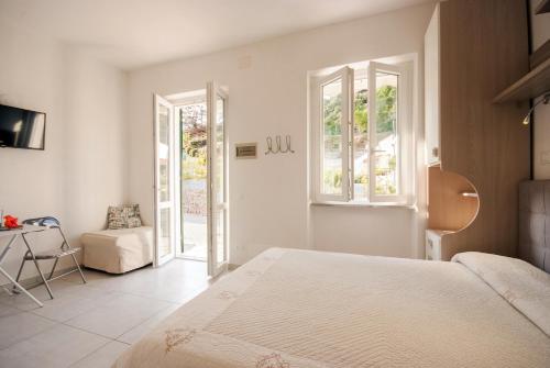 a white bedroom with a bed and a chair at Cala Azzurra in Marciana